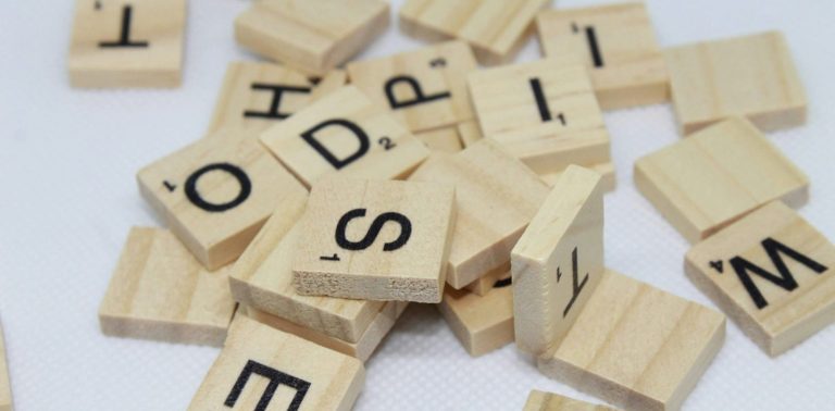 Holzplättchen mit Buchstaben liegen ungeordnet auf dem Tisch